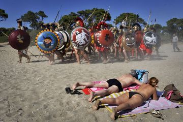 Sunbathers watch Italian re-enactors dressed as Greek hoplites perform the 490 BC battle of Marathon Sunbathers watch Italian re-enactors dressed as Greek hoplites perform the 490 BC battle of Marathon