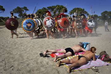 Sunbathers watch Italian re-enactors dressed as Greek hoplites perform the 490 BC battle of Marathon