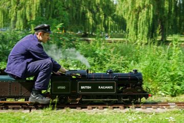 St Neots, Cambridgeshire, England - May 05, 2022 Miniature Steam train and driver in the park.
