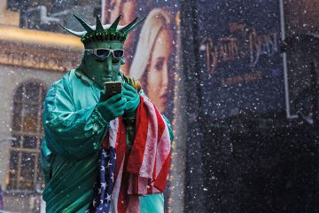 A man dressed up as the Statue of Liberty holding a mobile