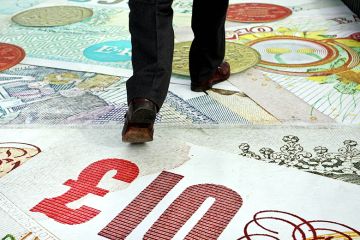 A pedestrian crosses the Millenium Bridge as MasterCard signage depicting banknotes carpets the bridge to launch its "PayPass" cashless card system, in London, U.K., 2007. To illustrate stepped loan repayments.