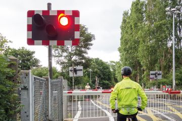 A cyclist stops at a red light at a level crossing to illustrate PhD enrolment hangs on an email
