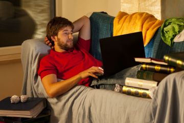 Student on laptop surrounded by books Student on laptop surrounded by books