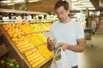 Surprised man reading receipt in grocery store