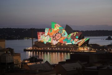 The sails of the Sydney Opera House lit up with an aboriginal design