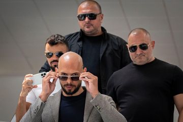 Andrew Tate walks with bodyguards Andrew Tate walks with bodyguards to illustrate Should we be worried about Andrew Tate’s ‘anti-university’ university