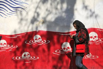 A woman walks past an anti-American murals following a possible US intervention against Iran on 28 January, 2026 in Tehran, Iran.