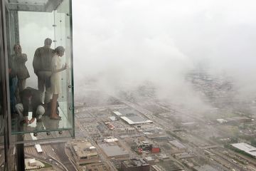 Visitors stand out on the Ledge, a glass cube that juts out from the 103rd floor Skydeck of the Sears Tower, Chicago Visitors stand out on the Ledge, a glass cube that juts out from the 103rd floor Skydeck of the Sears Tower, Chicago