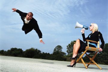 Businesswoman with megaphone shouting at man flying, outdoors Businesswoman with megaphone shouting at man flying, outdoors