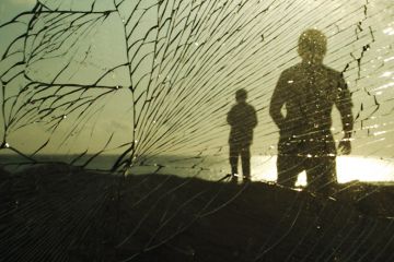 Silhouettes of people behind broken glass