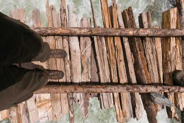 Person crossing river on wooden bridge