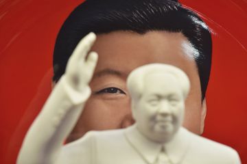 A decorative plate featuring an image of Chinese President Xi Jinping behind a statue of late communist leader Mao Zedong in a shop