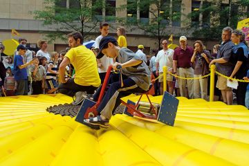 Visitors to the World Science Festival Street Fair peddle a square wheeled tricycle