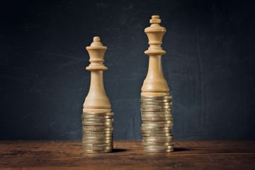 King and Queen chess pieces on pile of coins King and Queen chess pieces on pile of coins