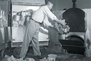 Old and tattered money being tossed into a furnace