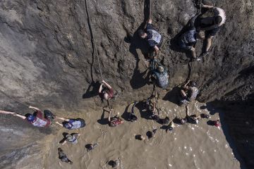 Participants climb up a wall during the Race of Heroes obstacle course event.