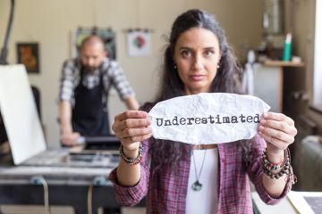 Young female lithography worker holding a sign "underestimated" Young female lithography worker holding a sign "underestimated"
