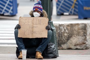 A homeless person wearing gloves and a protective mask sits with a sign that reads, "Seeking Human Kindness" amid the coronavirus pandemic on April 19, 2020 in New York City, United States. A homeless person wearing gloves and a protective mask sits with a sign that reads, "Seeking Human Kindness" amid the coronavirus pandemic on April 19, 2020 in New York City, United States.
