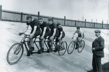 A four-man cycling tandem team in training with the 'chase and pacemaker' whilst being timed on the stopwatch. A four-man cycling tandem team in training with the 'chase and pacemaker' whilst being timed on the stopwatch.