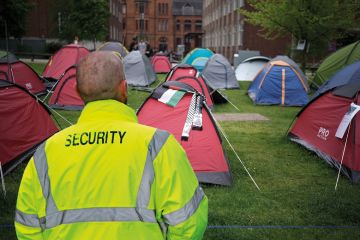 Montage of a security guard looking at tents elonging to pro-Palestinian protesters camping outside Manchester University `montage of a security guard looking at tents elonging to pro-Palestinian protesters camping outside Manchester University to illustrate We security guards won’t be taking the US approach to encampments