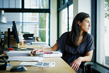 Woman looking out of window whilst at desk