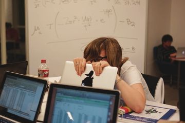 A student hides behind her laptop