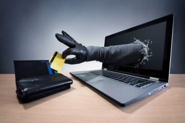 A hand comes out of a computer screen and steals a credit card