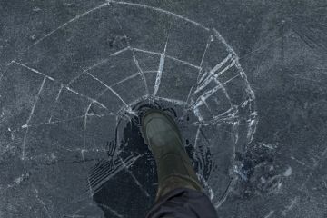 A person walks on cracking ice, symbolising precarity