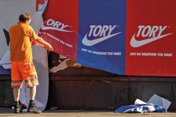 A maintenance worker removes posters depicting the Nike logo and reading ‘Tory just do whatever you want’ from a wall in East London on May 30, 2020, England. A maintenance worker removes posters depicting the Nike logo and reading ‘Tory just do whatever you want’ from a wall in Shoreditch, East London, on May 30, 2020, England.