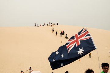 Tourists sliding sand board down the sand dunes in Port Stephen, Australia Tourists sliding sand board down the sand dunes in Port Stephen, Australia