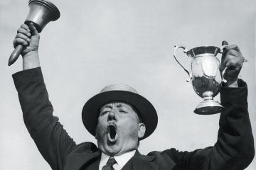 Man ringing bell while holding trophy