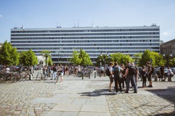 A large rectangular building with several students and bikes near it 