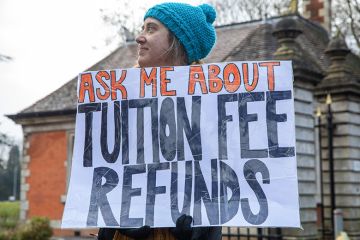 A university staff member from the University and College Union (UCU) stands holding a sign stating "ask me about tuition fee refunds" at an official picket outside Royal Holloway University of London on the first day of strike action, 9 February, 2023.