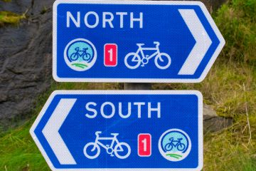 Two white on blue signs for the UK National Cycle Route 1 in Lerwick, Shetland, Scotland, UK - one pointing North, the other pointing South. stock photo