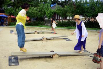 Two women playing on a Korean See Saw,Neolttwigi or nol-ttwigiis a traditional game of Korea typically played by women and girls on traditional holidays such as Korean New Year, Chuseok, and Dano. in the Wolmi Park in Seoul, South Korea Two women playing on a Korean See Saw,Neolttwigi or nol-ttwigiis a traditional game of Korea typically played by women and girls on traditional holidays such as Korean New Year, Chuseok, and Dano. in the Wolmi Park in Seoul, South Korea