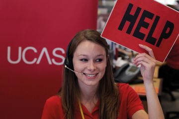 An employee in the UCAS clearing house call centre calls for assistance and advice from a supervisor