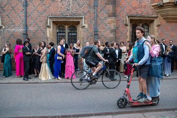 University of Cambridge students going to the Trinity College May Ball, as people ride past on a scooter. To illustrate that elite universities admit fewer local students as intakes grow. University of Cambridge students going to the Trinity College May Ball, as people ride past on a scooter. To illustrate that elite universities admit fewer local students as intakes grow.