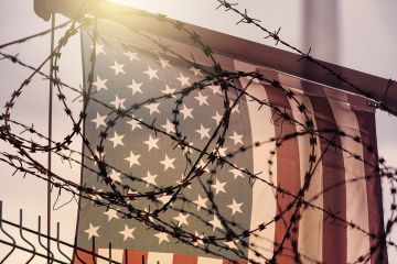 Barbed wire in front of the American flag, symbolising the crackdown on international students