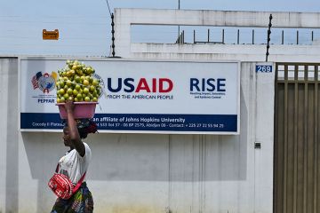 A street vendor walks past the USAID office in Abidjan, Ivory Coast