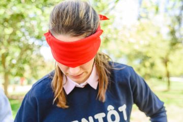 Valencia, Spain - April 7, 2019 Group of young people in an outdoor school playing cover their eyes with a red veil to find the partner, and thus develop social skills.