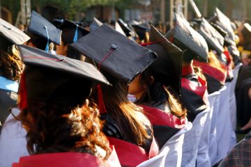 VALENZUELA CITY, PHILIPPINES - APRIL 30, 2019 College students in their graduation attire or Toga sit and wait for their turn to be called to go up on stage to get their diploma.