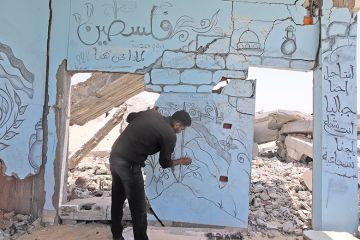 Palestinian artist draws Palestinian flag and Al-Aqsa Mosque, symbolising solidarity in Gaza, on the wall of a building that was heavily damaged as a result of the attacks in Rafah, Gaza on 30 April, 2024