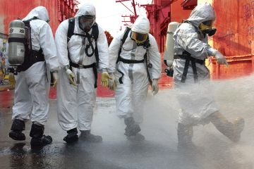 People in protective gear spraying water People in protective gear spraying water