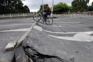 Tania Flowers rides her bike onto a damaged bridge over the Avon River Tania Flowers rides her bike onto a damaged bridge over the Avon River to illustrate New Zealand scraps research reforms and infrastructure funding