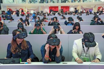 Members of the media wear virtual reality headsets in Shenzhen, Guangdong Province of China to illustrate AI-generated lecturers take a turn at Hong Kong university