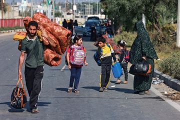 People carrying some of their belongings reach the central Gaza Strip People carrying some of their belongings reach the central Gaza Strip to illustrate Gaza war drives scholars’ exodus