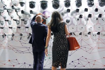 People look at surveillance cameras at the annual Huawei Connect event in Shanghai, China to illustrate Party strengthens control of Chinese university administration