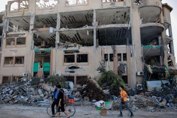 Palestinians walks past the destroyed building of the Islamic University in Gaza City to illustrate Academia in Gaza ‘has been destroyed’ by Israeli ‘educide’