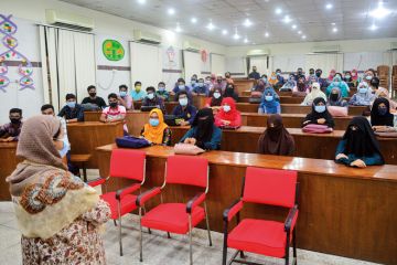 Dhaka University students wearing face masks attend their class 