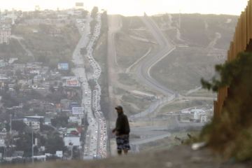 A man walks on the Mexican side of the U.S.-Mexico border barrier 